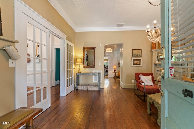 foyer entrance with ornamental molding, an inviting chandelier, dark hardwood / wood-style floors, and french doors