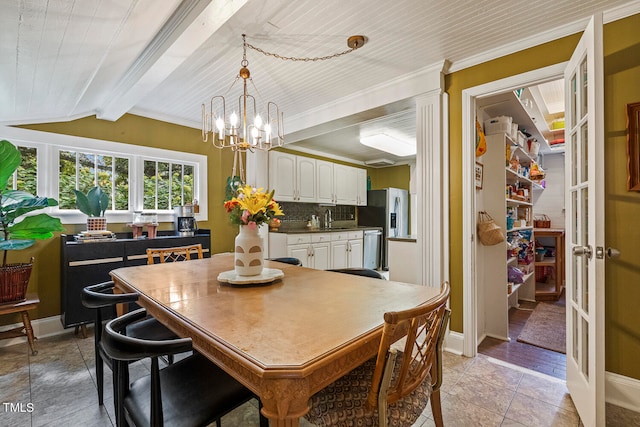 tiled dining space with an inviting chandelier, vaulted ceiling with beams, crown molding, and sink