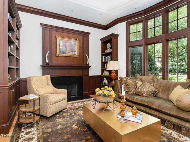 living room featuring built in features, ornamental molding, and dark hardwood / wood-style flooring