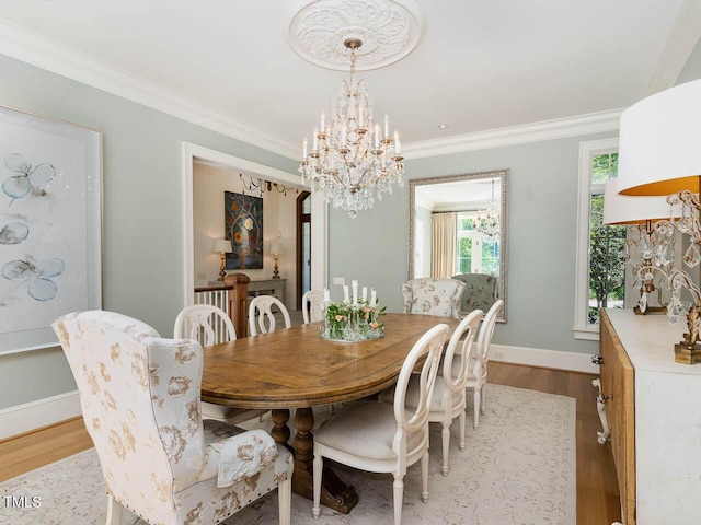 dining room featuring a notable chandelier, crown molding, baseboards, and wood finished floors
