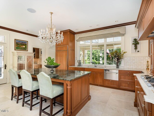 kitchen with dark stone countertops, backsplash, decorative light fixtures, a kitchen bar, and a kitchen island