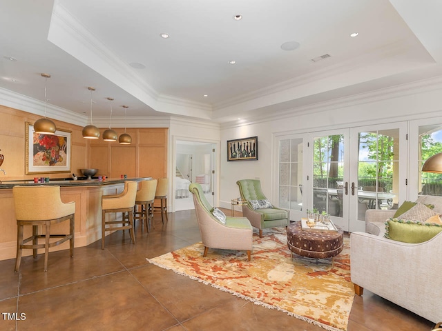 living room featuring a tray ceiling, french doors, and ornamental molding