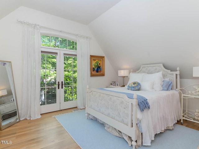 bedroom featuring access to exterior, vaulted ceiling, light wood-type flooring, and french doors