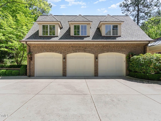 view of front of home featuring driveway, brick siding, and a garage