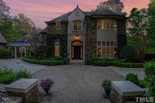 french provincial home featuring stone siding, driveway, and a chimney