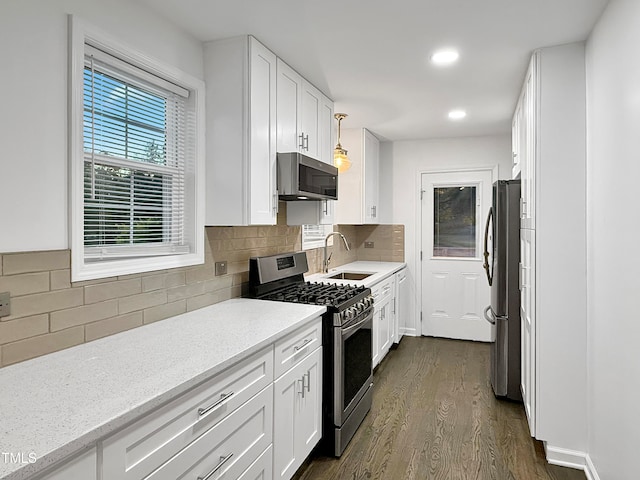 kitchen with sink, dark hardwood / wood-style flooring, hanging light fixtures, white cabinetry, and stainless steel appliances