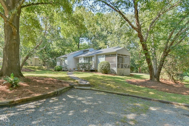 view of front facade with a sunroom and a front lawn