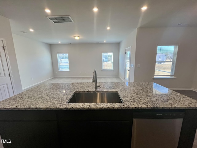 kitchen with sink, stainless steel dishwasher, an island with sink, plenty of natural light, and light stone counters