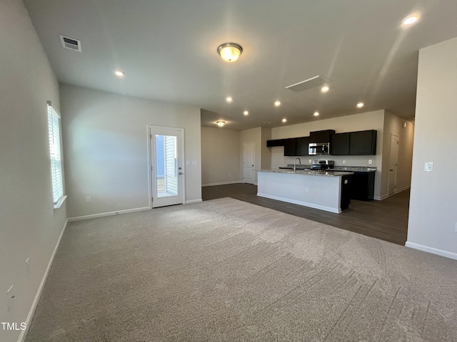 unfurnished living room featuring dark carpet and sink