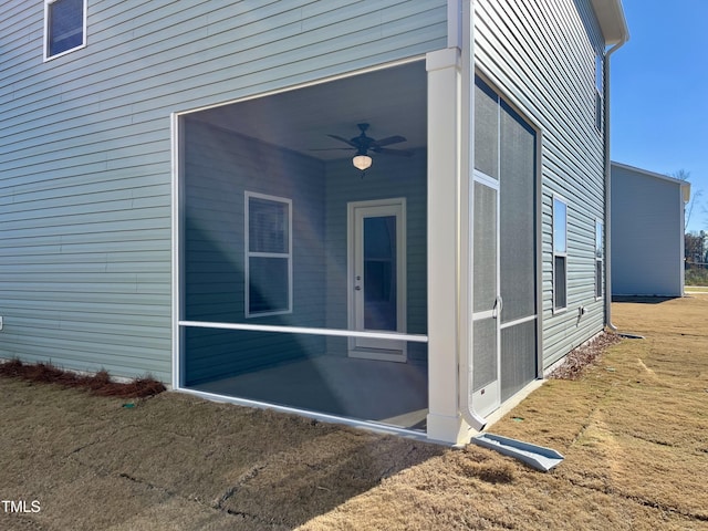 entrance to property with a lawn and ceiling fan