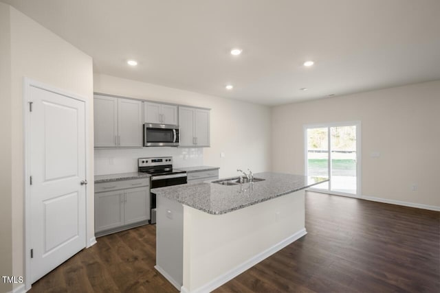 kitchen with sink, a kitchen island with sink, stainless steel appliances, and dark hardwood / wood-style floors