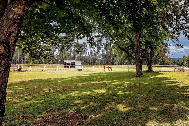 view of yard with an outbuilding, a rural view, and fence