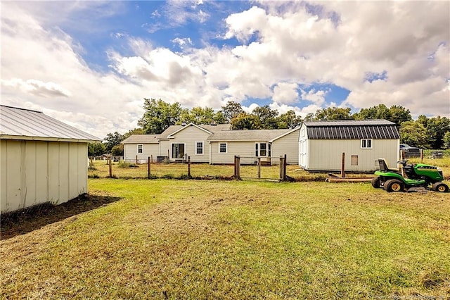 rear view of house with fence, a storage unit, an outbuilding, and a yard