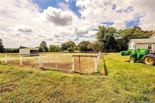 view of yard featuring a rural view, fence, and an outbuilding