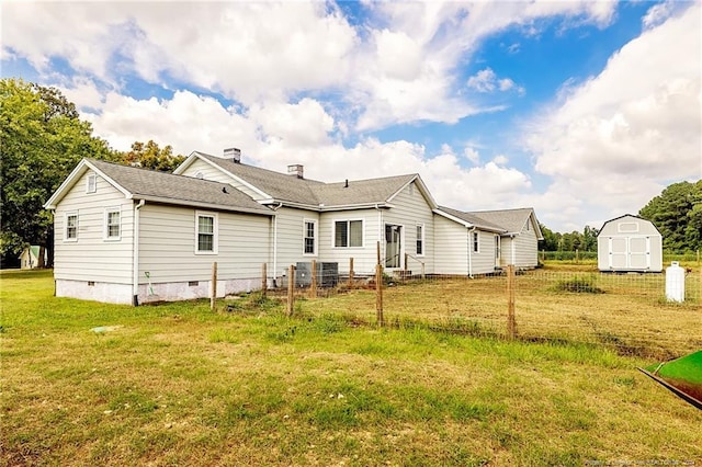 rear view of house with an outbuilding, roof with shingles, crawl space, a lawn, and a shed