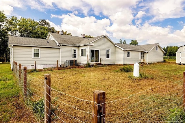 back of house with entry steps, a lawn, central AC, and an outdoor structure