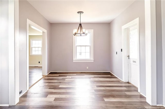 unfurnished dining area featuring a chandelier and wood finished floors