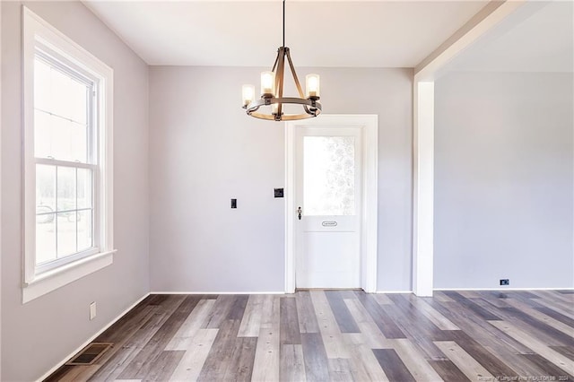 unfurnished dining area with visible vents, an inviting chandelier, and wood finished floors