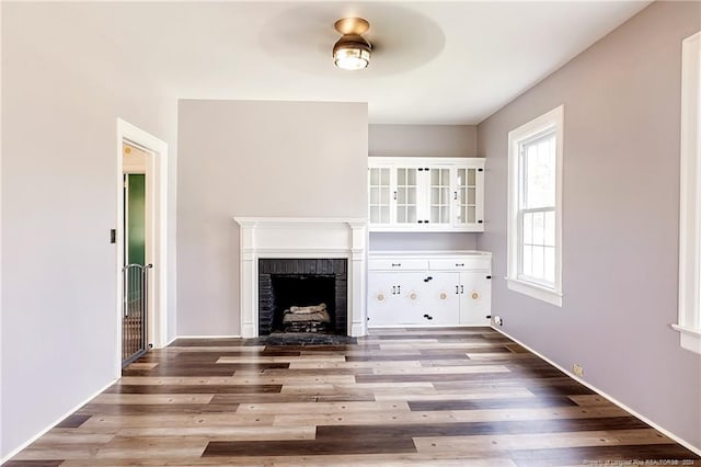 unfurnished living room with a brick fireplace and wood finished floors