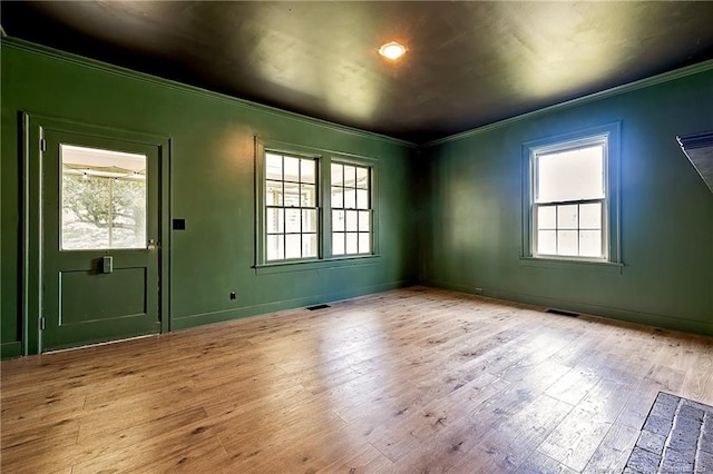 spare room featuring baseboards, visible vents, ornamental molding, and wood finished floors