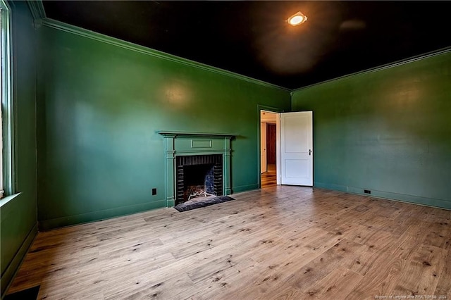 unfurnished living room with a fireplace, ornamental molding, and wood finished floors