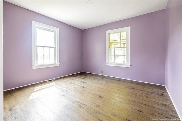 empty room featuring wood finished floors and visible vents