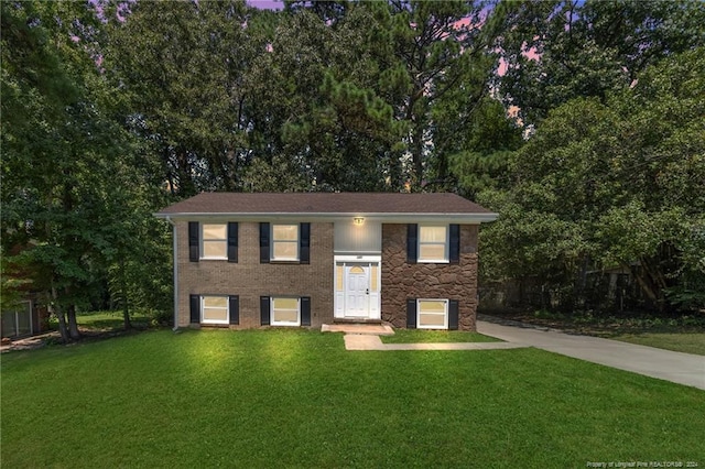 bi-level home with a front yard and brick siding