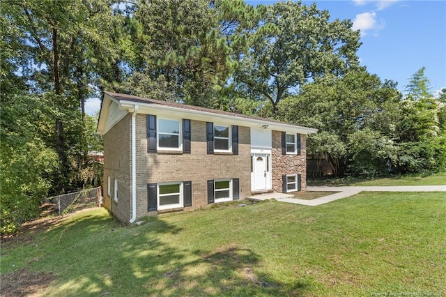 bi-level home featuring brick siding, a front yard, and fence