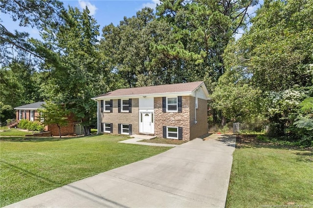 split foyer home featuring stone siding, concrete driveway, fence, and a front lawn