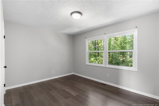 empty room featuring dark wood-type flooring and a textured ceiling