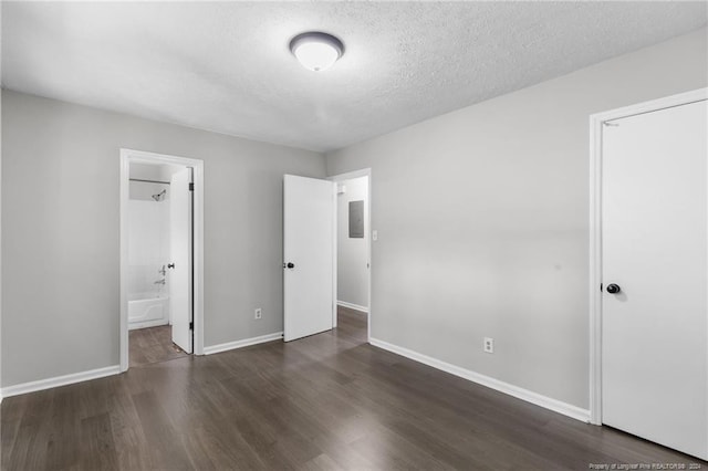 unfurnished bedroom featuring dark wood-type flooring, connected bathroom, and a textured ceiling