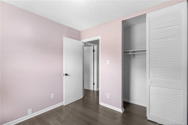 unfurnished bedroom with dark wood-type flooring and a closet