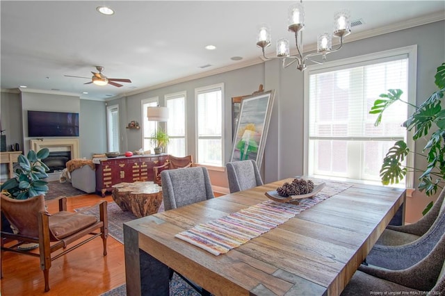 dining room with crown molding, ceiling fan with notable chandelier, and wood-type flooring