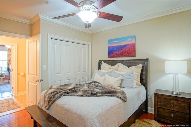 bedroom with crown molding, ceiling fan, a closet, and hardwood / wood-style flooring