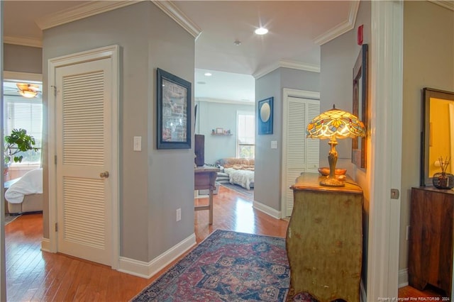 hallway with light hardwood / wood-style floors and crown molding