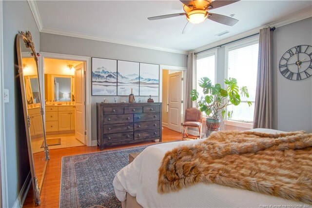 bedroom featuring ceiling fan, hardwood / wood-style flooring, ensuite bathroom, and crown molding