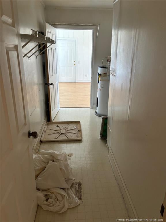 hallway featuring electric water heater and light tile patterned floors