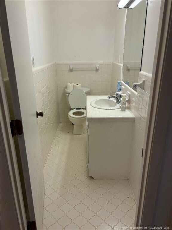 bathroom with tile patterned flooring, backsplash, toilet, tile walls, and vanity