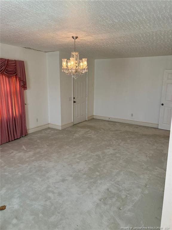 unfurnished room featuring an inviting chandelier and a textured ceiling