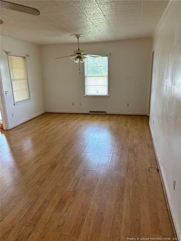 spare room with baseboard heating, crown molding, ceiling fan, and hardwood / wood-style flooring