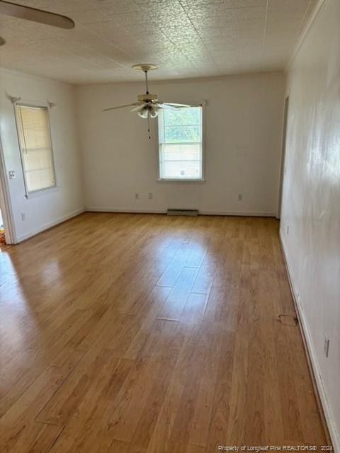 spare room with wood-type flooring, a baseboard radiator, and ceiling fan