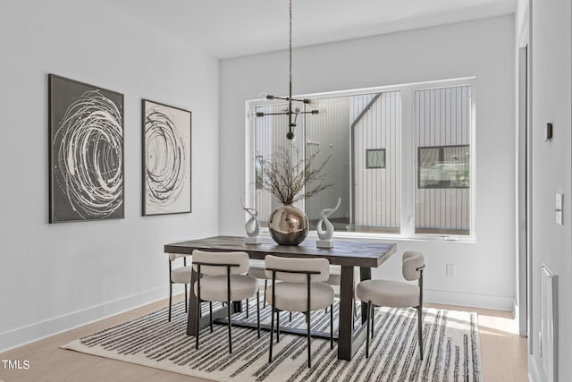 dining room with light hardwood / wood-style floors and a chandelier