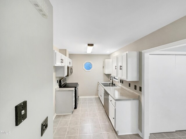 kitchen with appliances with stainless steel finishes, light tile patterned flooring, sink, and white cabinets