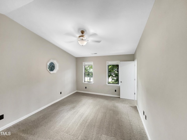 carpeted empty room with visible vents, ceiling fan, and baseboards