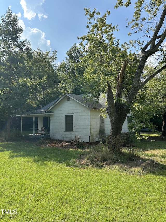 view of side of home with a yard, concrete block siding, and a porch