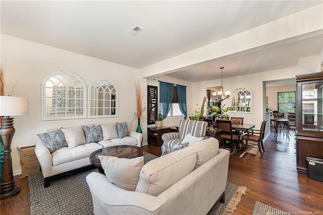 living area with an inviting chandelier, dark wood-style floors, visible vents, and baseboards