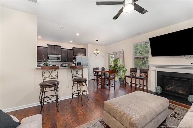 living room with ceiling fan with notable chandelier and dark wood-type flooring