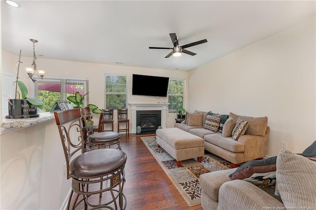 living area with a wealth of natural light, a glass covered fireplace, dark wood finished floors, and a ceiling fan