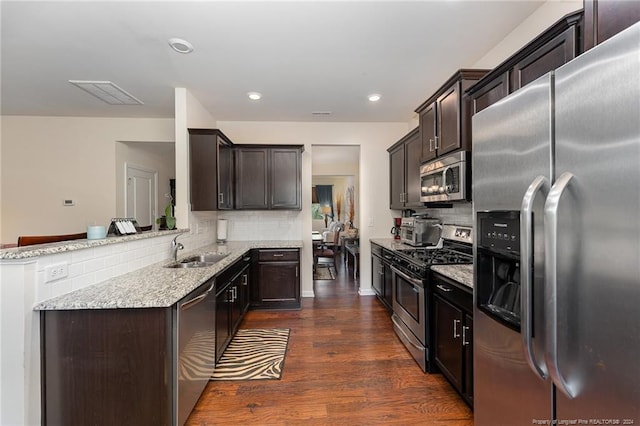 kitchen featuring tasteful backsplash, dark hardwood / wood-style flooring, kitchen peninsula, sink, and appliances with stainless steel finishes