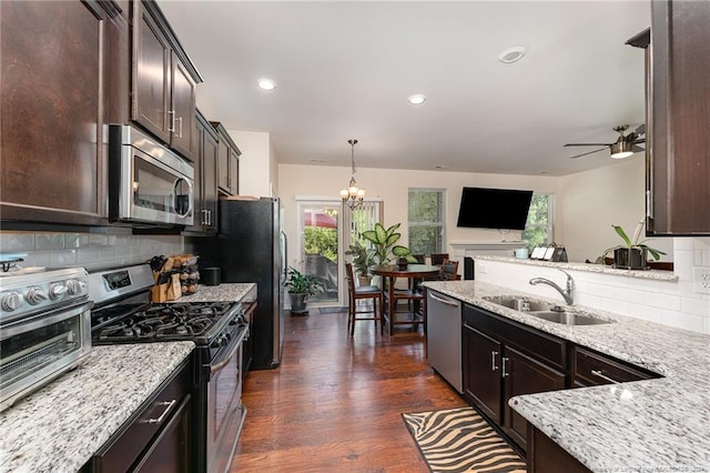 kitchen with backsplash, appliances with stainless steel finishes, dark wood-type flooring, sink, and light stone counters